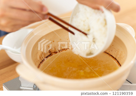 一名男子用雞鍋裡剩下的汁煮粥。 一名男子用雞鍋裡剩下的汁煮粥。 121190359