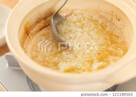 A man prepares rice porridge using leftover broth from a chicken hotpot 121190503