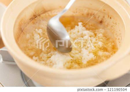 A man prepares rice porridge using leftover broth from a chicken hotpot 121190504