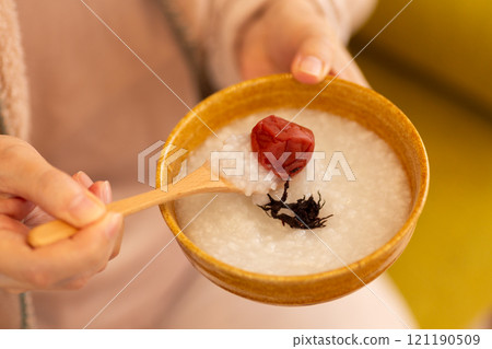The hands of a woman eating porridge with pickled plums The hands of a woman eating porridge with pickled plums 121190509