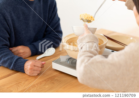 A middle-aged couple enjoying rice porridge with chicken hotpot soup 121190709