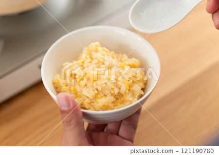 A middle-aged man makes and eats porridge as a finishing touch to a hotpot meal 121190780