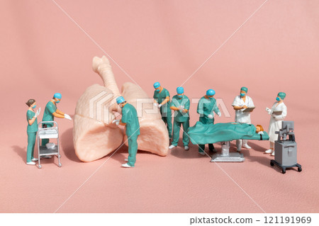 Miniature figures, medical team performing surgery on a detailed anatomical lung model 121191969