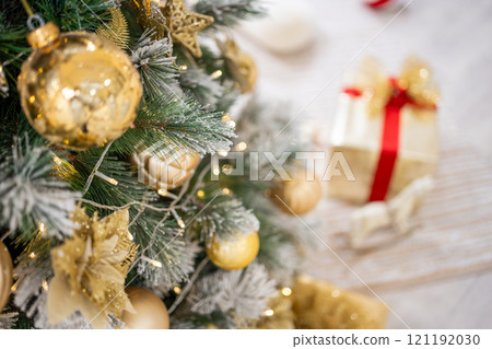 Christmas tree with gold toys. Festively decorated Christmas tree with garlands. Symbol of the new year in trend colors 121192030
