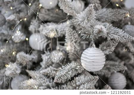 Christmas tree with silver toys. Festively decorated Christmas tree with garlands. Symbol of the new year in trend colors 121192031