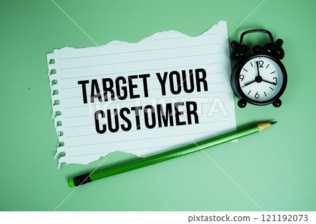 Target Your Customers text written on paper card with alarm clcok on green background 121192073