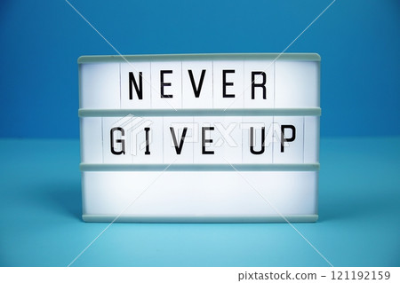 Never Give Up letterboard text on LED Lightbox on blue background 121192159