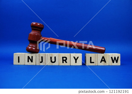 Injury Law alphabet letters with wooden blocks alphabet letters and Gavel on blue background 121192191