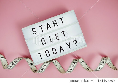Start diet today? letterboard text on LED Lightbox and Measuring tape on pink background, Healthcare concept Start diet today? letterboard text on LED Lightbox and Measuring tape on pink background, Healthcare concept 121192202
