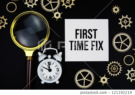 First Time Fix text message on sticky note with magnifying glass and alarm clock on black background 121192219