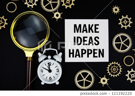 Make Ideas Happen text message on sticky note with magnifying glass and alarm clock on black background 121192220