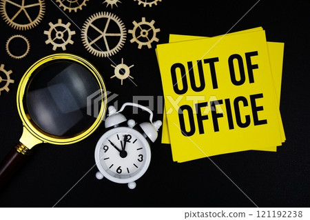 Out Of Office text message on sticky note with magnifying glass and alarm clock on black background Out Of Office text message on sticky note with magnifying glass and alarm clock on black background 121192238