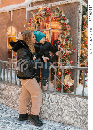 Mother and a child are standing on a balcony looking at a Christmas tree Mother and a child are standing on a balcony looking at a Christmas tree 121192413
