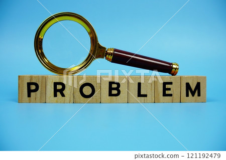 Problem with wooden blocks alphabet letters and Magnifying glass on blue background 121192479