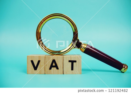 VAT with wooden blocks alphabet letters and Magnifying glass on blue background 121192482