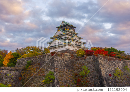 Osaka Castle tower at dusk, surrounded by autumn leaves 121192904
