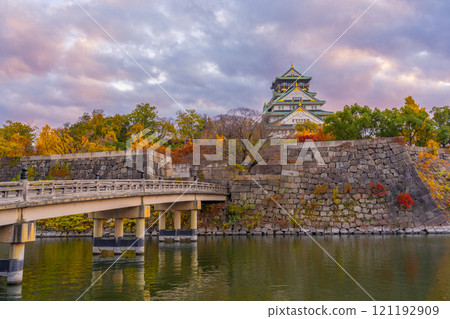 Osaka Castle and Gokuraku Bridge at dusk, surrounded by autumn leaves 121192909