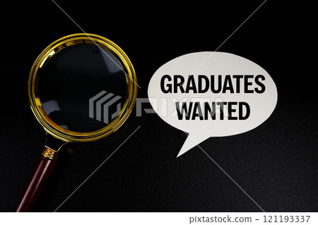 Graduates wanted text on speech bubble with magnifying glass top view on black background 121193337