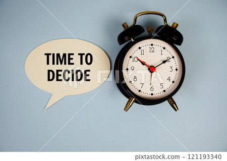Time to dicide text on speech bubble with alarm clock top view on blue background 121193340