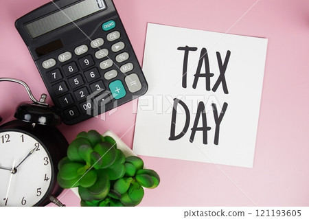 Tax Day text with calculator and alarm clock on pink background Tax Day text with calculator and alarm clock on pink background 121193605