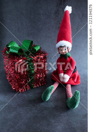 Christmas elf doll with a gift on dark background Christmas elf doll with a gift on dark background 121194876