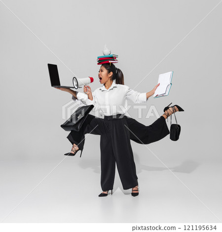 Young woman, worker in business attire holds megaphone, laptop, and planner while balancing books. Concept of leadership, communication, and multitasking. Young woman, worker in business attire holds megaphone, laptop, and planner while balancing books. Concept of leadership, communication, and multitasking. 121195634
