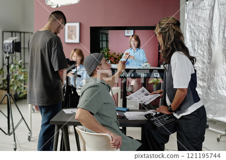 Male professional director discussing essential props with assistant director who looking at big screen while operator setting camera Male professional director discussing essential props with assistant director who looking at big screen while operator setting camera 121195744