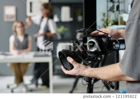 Medium close up of unrecognizable operators hands holding massive professional lens Medium close up of unrecognizable operators hands holding massive professional lens 121195822