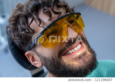 Patient has cosmetic dental treatment using modern laser machine to whiten teeth with fluoride paste 121196087