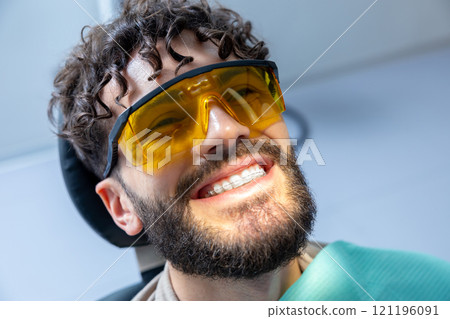 Patient has cosmetic dental treatment using modern laser machine to whiten teeth with fluoride paste Patient has cosmetic dental treatment using modern laser machine to whiten teeth with fluoride paste 121196091