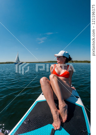 Woman Relaxing on Paddleboard in Summer 121196175