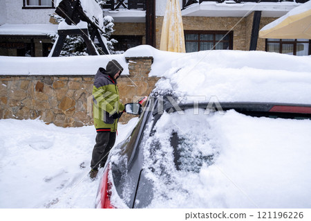 Person Clearing Snow from Car in Winter Landscape Person Clearing Snow from Car in Winter Landscape 121196226