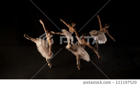Lightness and weightlessness. Graceful and elegant ballerinas in white tutus in motion, creating striking visual, dancing on dark stage 121197520