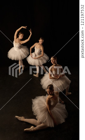 Creative composition of four elegant young girls, ballerinas in white classical tutus performing with grace on dark background 121197532