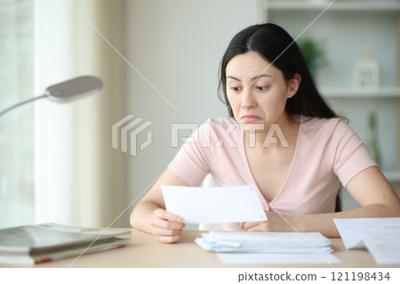Perplexed asian woman checking bill Perplexed asian woman checking bill 121198434