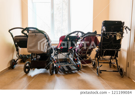 A Line of Various Strollers Against a Window in a Bright Room 121199084