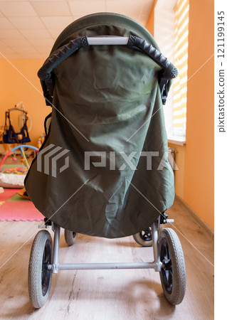 Back View of a Green Stroller in a Child-Friendly Room 121199145