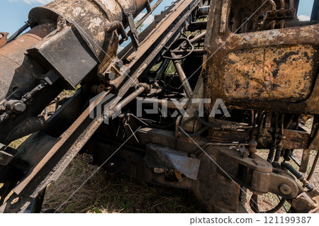 Rusty Excavator Components in a Lush Green Field 121199387
