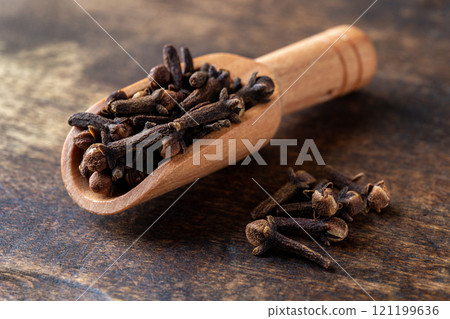 Dry clove buds in a wooden scoop macro. Dry clove buds in a wooden scoop macro. 121199636