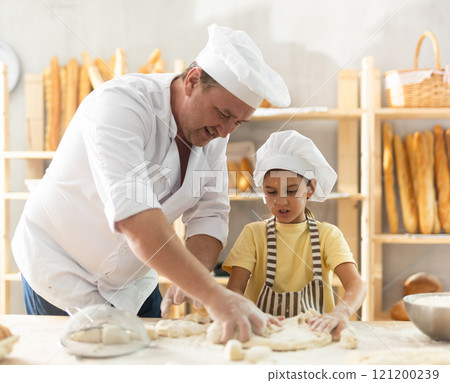 Father and daughter roll out dough together to make delicious bread 121200239