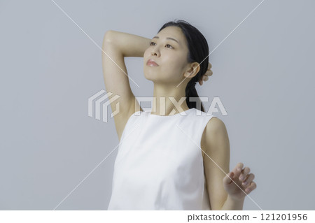 Portrait of a young woman wearing a white dress against a gray background 121201956