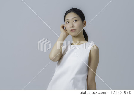 灰色背景下穿著白色連身裙的年輕女子的肖像 灰色背景下穿著白色連身裙的年輕女子的肖像 121201958