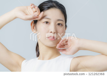Portrait of a young woman wearing a white dress against a gray background Portrait of a young woman wearing a white dress against a gray background 121202368