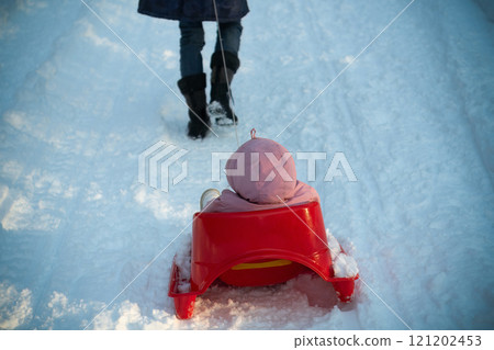 Child Pulled on a Sled by Mother on Snowy Winter Trail Fun Child Pulled on a Sled by Mother on Snowy Winter Trail Fun 121202453
