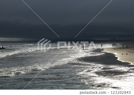 In the evening, as the clouds begin to hang low, the waves and the silhouettes of surfers shine in the sunlight at Kugenuma Beach. In the evening, as the clouds begin to hang low, the waves and the silhouettes of surfers shine in the sunlight at Kugenuma Beach. 121202843