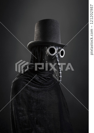 Plague doctor with black vintage top hat at night over dark misty background  121202987