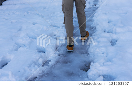 Male feet on a path covered with ice among the snow in winter after snowfall Male feet on a path covered with ice among the snow in winter after snowfall 121203507