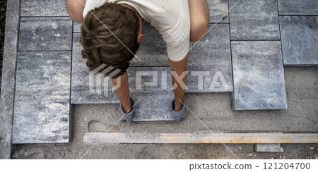 Man in a DIY project precisely laying grey concrete cement tiles Man in a DIY project precisely laying grey concrete cement tiles 121204700