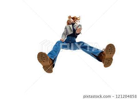 Fashionable young woman with flowing red hair wearing blue denim jeans and tan boots against white studio background. Bottom view Fashionable young woman with flowing red hair wearing blue denim jeans and tan boots against white studio background. Bottom view 121204858