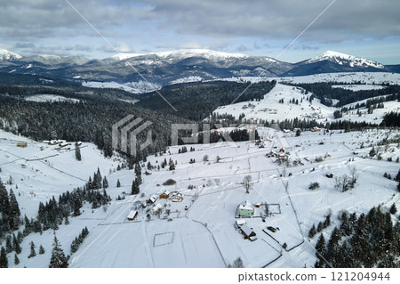 Winter landscape with small village houses between snow covered forest in cold mountains Winter landscape with small village houses between snow covered forest in cold mountains 121204944